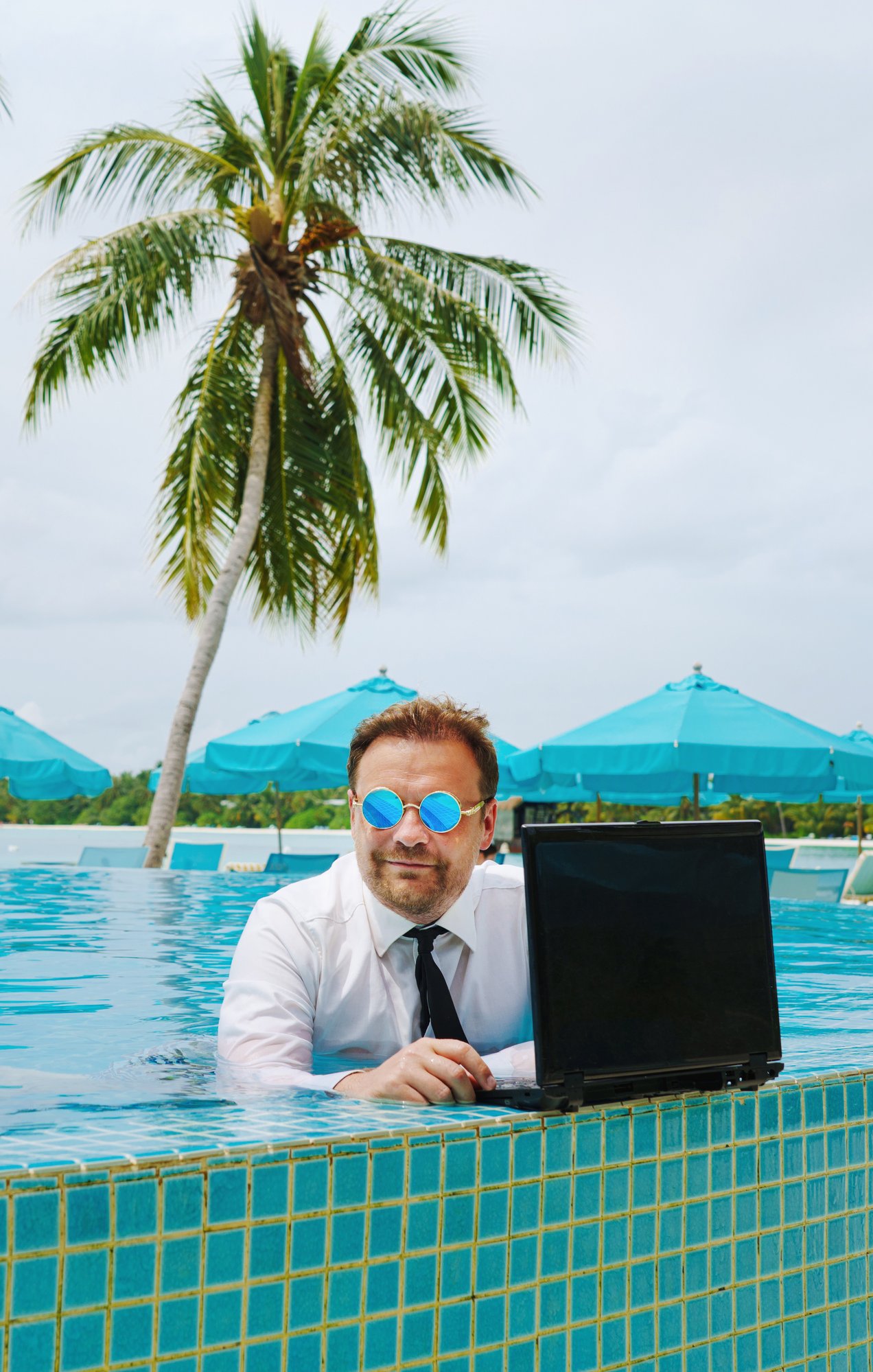 Man on laptop in swimming pool.