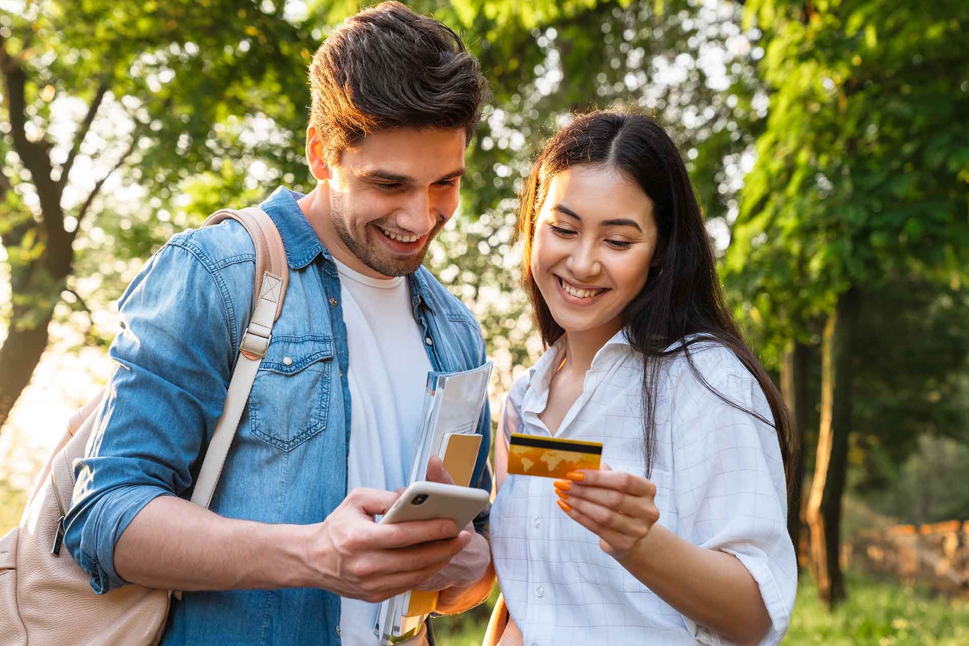 student couple booking on mobile phone and holding credit card